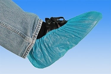 Schwarzer Schuh über den ein grüner Schuhüberzieher gestülpt wurde 